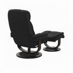 Black fabric Trevoux accent chair and matching ottoman showing the upholstered back, curved supports, and round bases, rear three-quarter view.