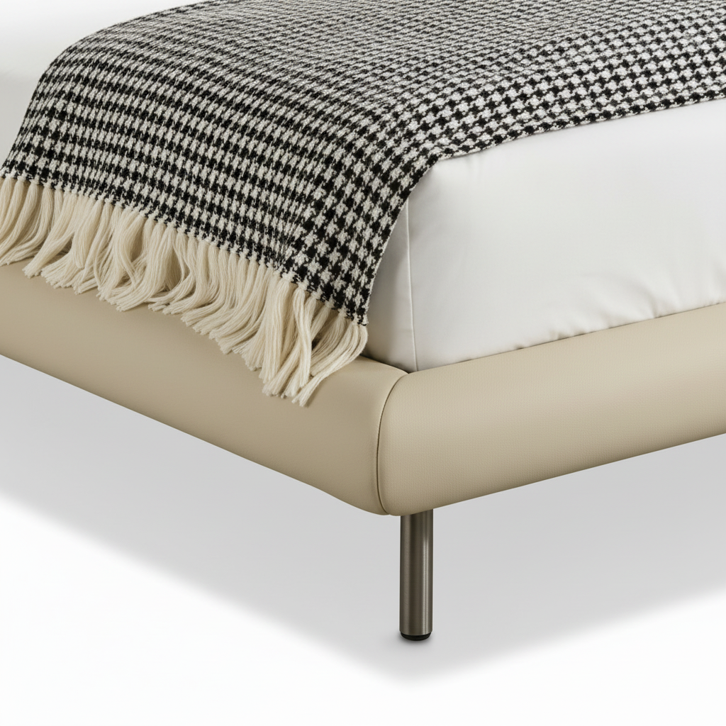 Bramwell Bed close-up of upholstered footboard, white bedding edge, patterned throw, and metal leg