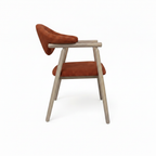 Thalia Dining Chair with rust orange upholstery and light wood, 90-degree side view on white background