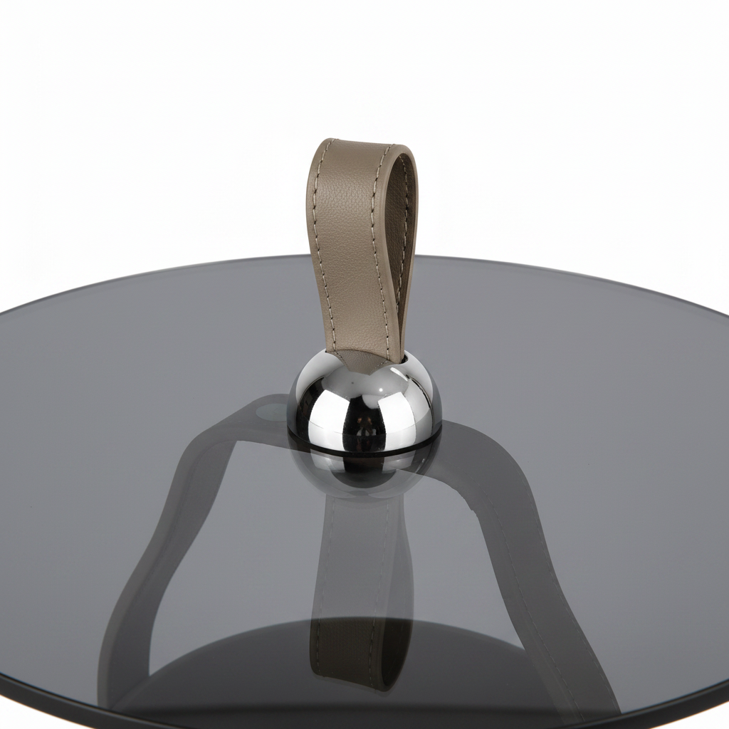 Close-up of the black tempered-glass tabletop, chrome connector, and leather loop on the Lorisse End Table
